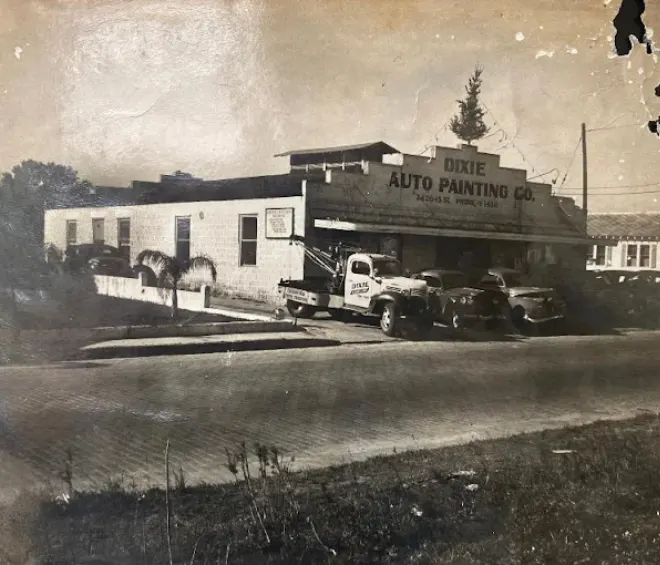 Vintage photo of the Dixie Auto Painting Co. shop with a tow truck and cars parked out front